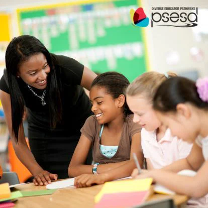 A young Black teacher smiles as she assists two young students.
