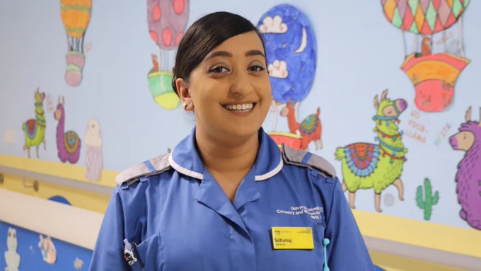 A picture of Sehanaj Kaur standing in her uniform on the Children's Ward at UHCW
