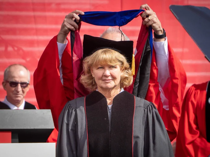 CALS alumna Debbie Hamrick receiving an honorary doctoral hood on stage at NC State's Spring Commencement. 