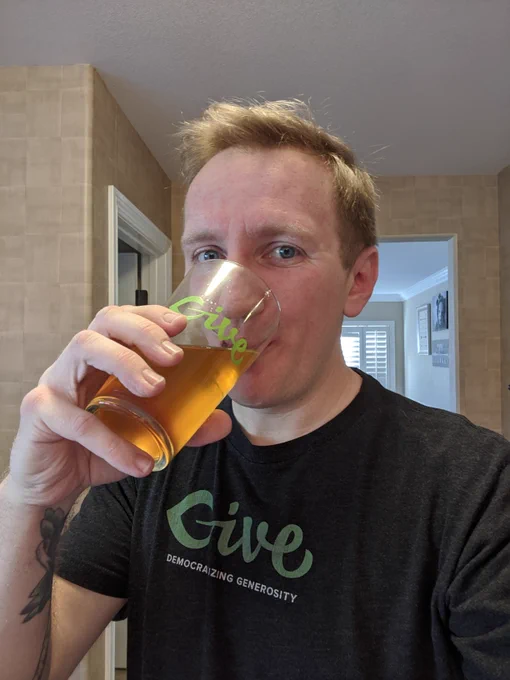 Russell Aaron drinking from GiveWP WordPress pintglass wearing a GiveWP tshirt