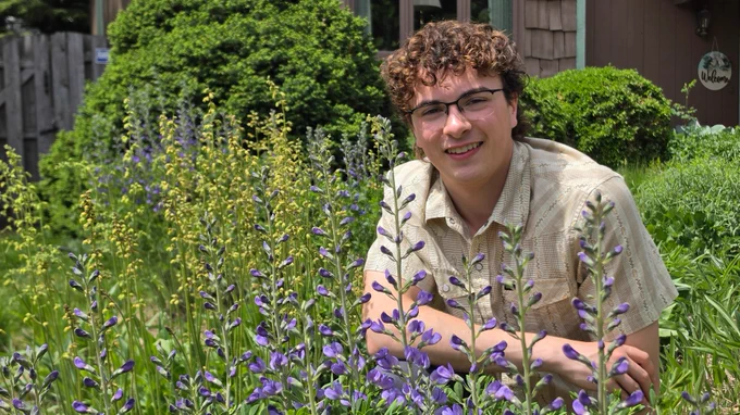 Man kneels in flower garden