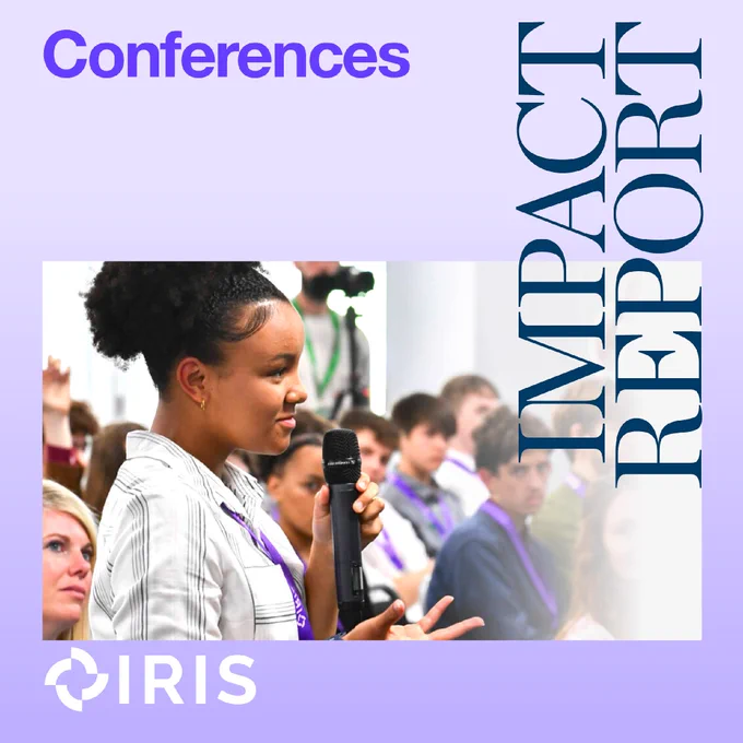 A picture of a person holding a microphone, speaking at a conference.