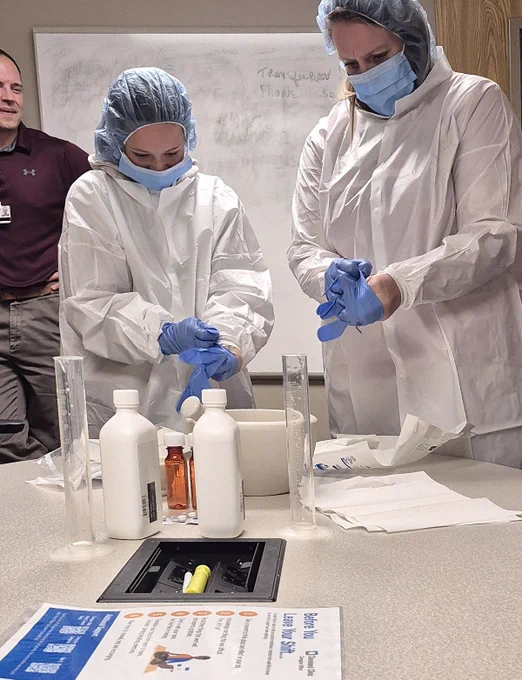Students in protective gowns, gloves, and masks participate in a hands-on lab demonstration during a site visit to Cleveland Clinic Union Hospital.