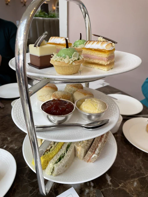 A three layer afternoon tea tower with sandwiches, mini scones and dainty cakes