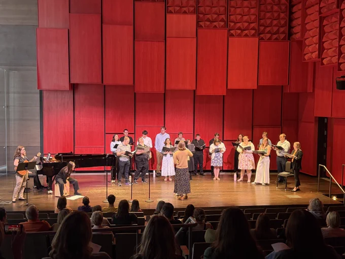 A choir stands on a stage, singing.