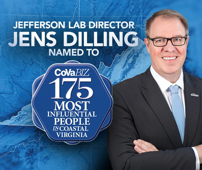 Person in a suit standing in front of a graphic featuring the text "Jefferson Lab Director Jens Dilling Named to CoVaBiz 175 Most Influential People in Coastal Virginia."