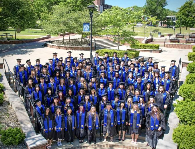 Large group shot of Morehead State’s Craft Academy Class of 2026 standing together in their graduation caps, gowns and blue stoles.