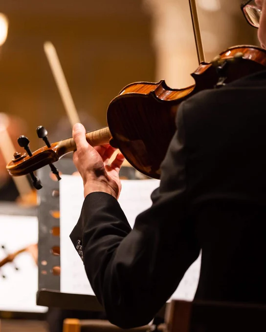 Close-up of a violinist's hands playing a wooden violin during a classical music performance.