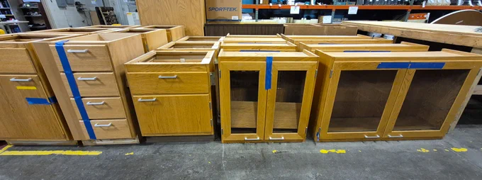Various wood base and wall cabinets lined up on the Surplus sales floor.