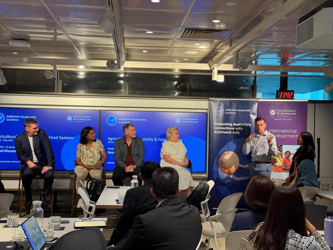 An Australian participant speaking to seated colleagues in front of two pull up banners, thanking four panellists seated in front of two digital screens showing the ASEAN-Australia Centre logo. 