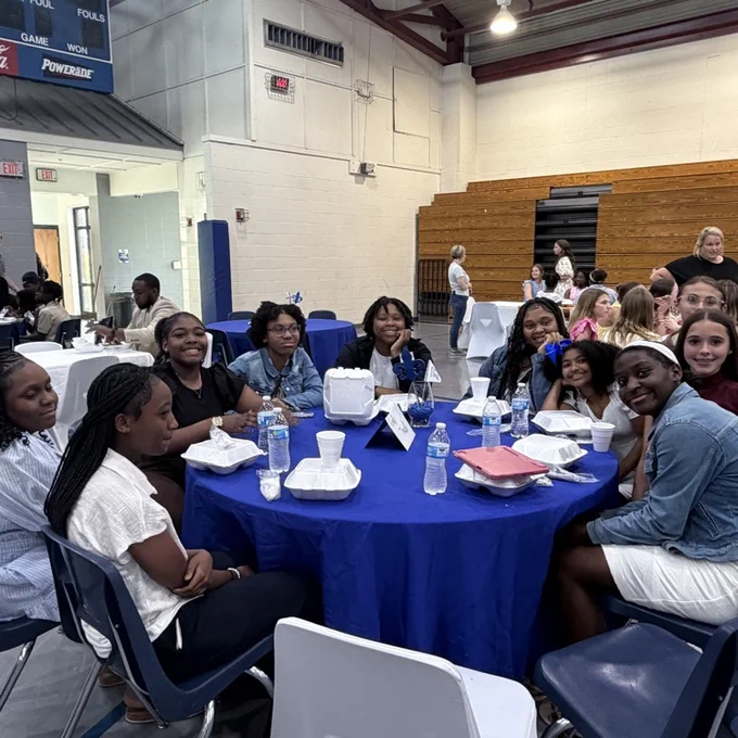 Students sit with teammates. 