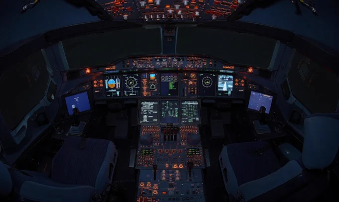 Illuminated cockpit of a commercial airplane showing detailed flight instruments and controls at night.