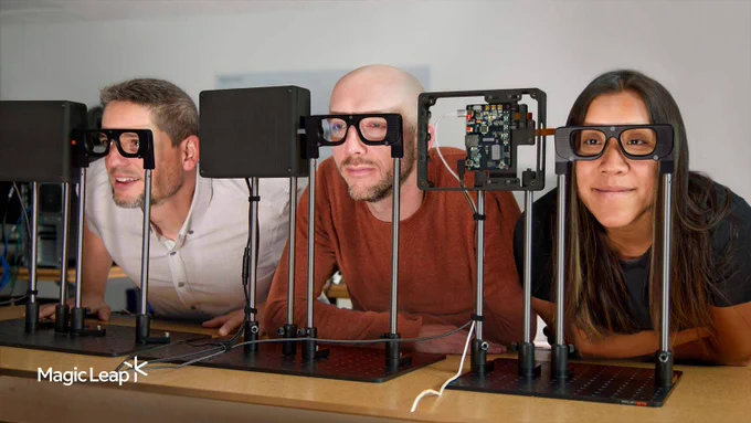 Three Magic Leap engineers look through AR glasses tabletop frame prototypes.