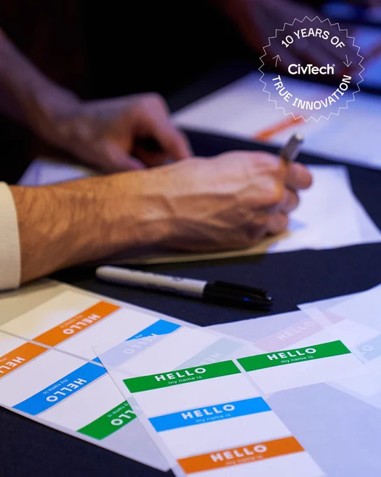 A table filled with name tag stickers and guest list sheet. A graphic overlay reads "10 Years of True Innovation"