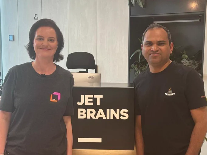 Marit van Dijk and Balkrishna Rawool standing next to the JetBrains logo at the office reception.
