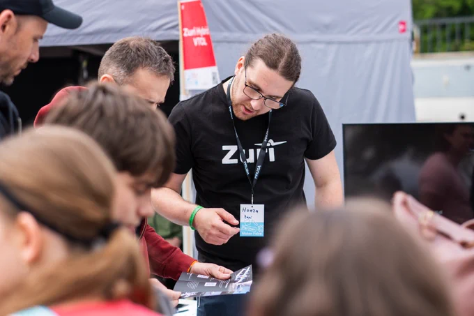 Zuri team member shows the Zuri brochure to visitors at the Maker Faire booth.