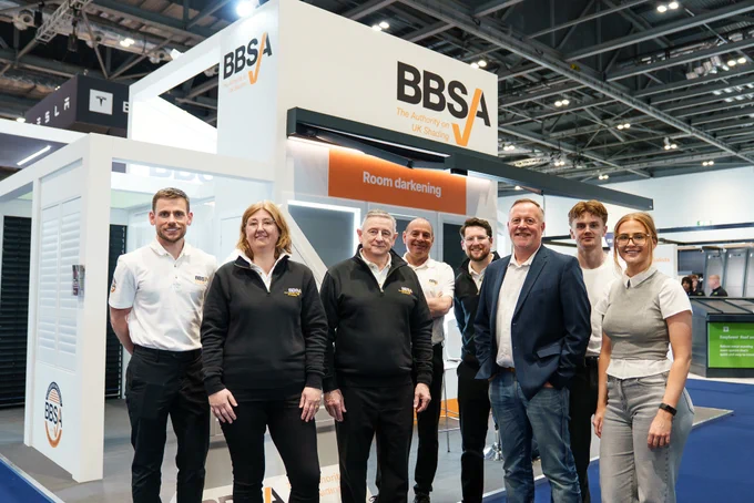 A group of BBSA representatives poses at their exhibition booth. The mood is professional and welcoming.