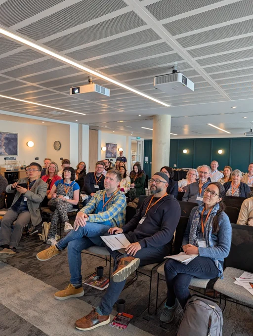 Room full of people sitting watching a presentation in a conference room