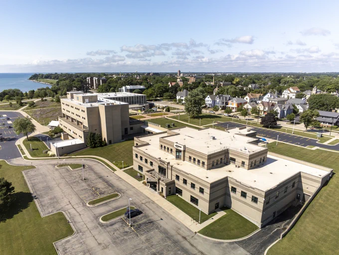 Aerial view of Gateway's Racine Campus with multiple beige buildings surrounded by green lawns and a nearby residential neighborhood under a clear sky.