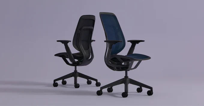 Two Steelcase Karman office chairs with mesh backs and adjustable armrests on caster wheels against a plain background.