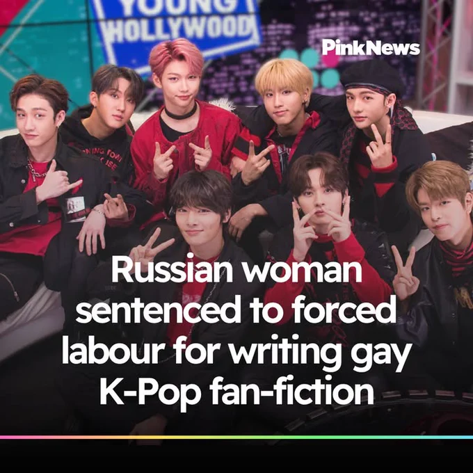 The image shows a group of eight individuals posing together, displaying peace signs. They are dressed in coordinated red and black outfits. The text on the image reads: "Russian woman sentenced to forced labour for writing gay K-Pop fan-fiction." Logos for "Young Hollywood" and "PinkNews" are visible.