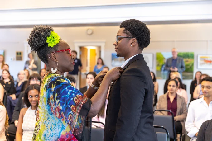 A woman places a pin on a student.