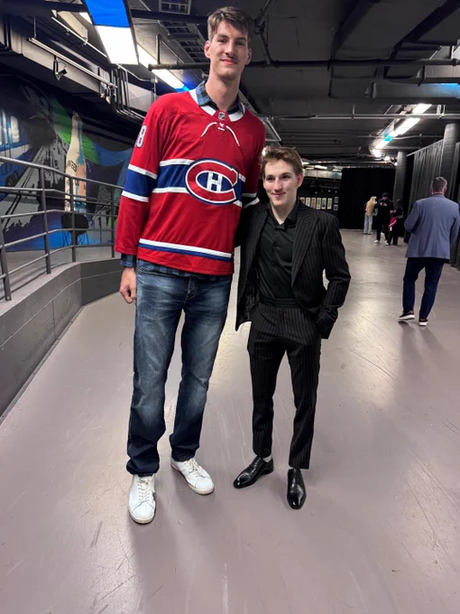 Olivier Rioux in a Canadiens jersey posing for a photo with Lane Hutson who is in a suit.