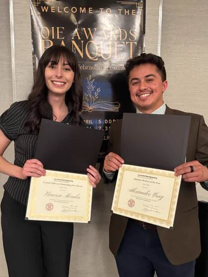 Vanessa Morales and Alexander Cruz stand together holding awards.
