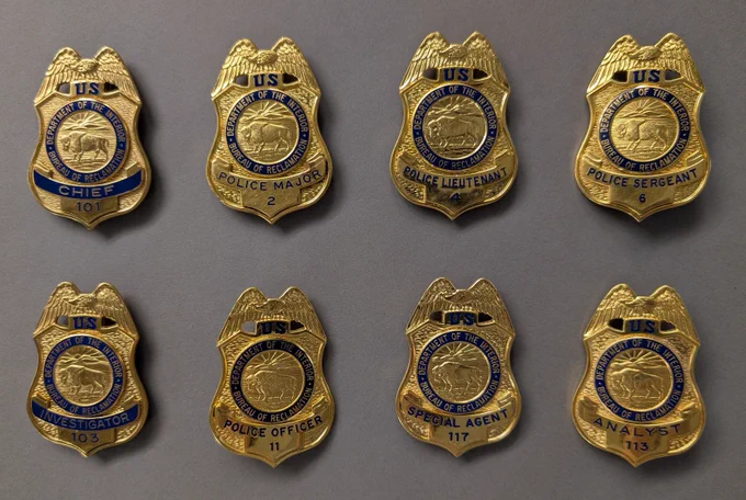 Eight police badges from the former Bureau of Reclamation Hoover Dam Police Department, each labeled with different ranks including Chief, Major, Lieutenant, and Sergeant.