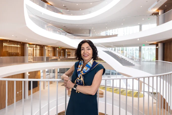 Dean Jennifer Chayes leans against the staircase railing inside the Barbara and Gerson Bakar Gateway, home of the UC Berkeley College of Computing, Data Science, and Society.
