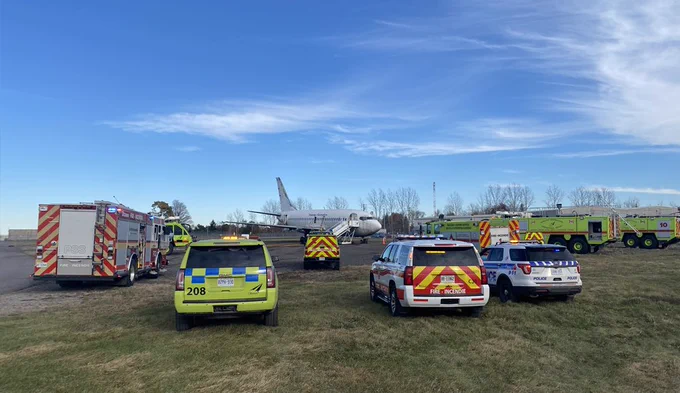 First responder vehicles parked in a semi-circle near a training aircraft / Véhicules des premiers intervenants garés en demi-cercle près d'un avion de formation