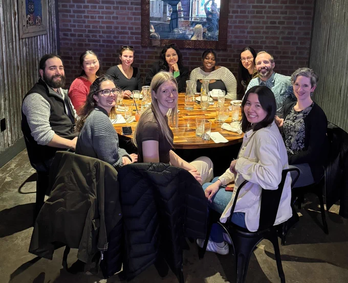11 lab members seated around a round table in front of a brick wall with a concrete floor. Clockwise from front: 
Ellie McVeigh
Defne Buyukyazgan
Matthew Maestri
Aiai Calmer
Hannah Hyde
M. Vanessa Rivera Núñez
Mmesoma Nwokolo
Katherine Conen
Brent Stewart 
Theresa Desrochers
Nami Kaneko
