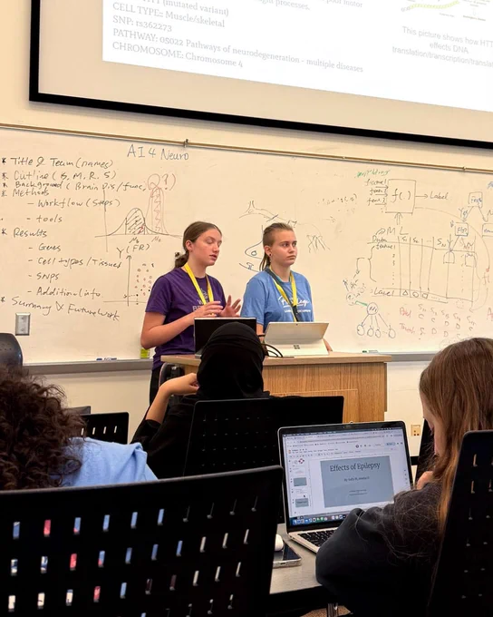 Two students in a UW-Madison Badger Precollege program for high school students. They are standing at a podium in front of a classroom. 