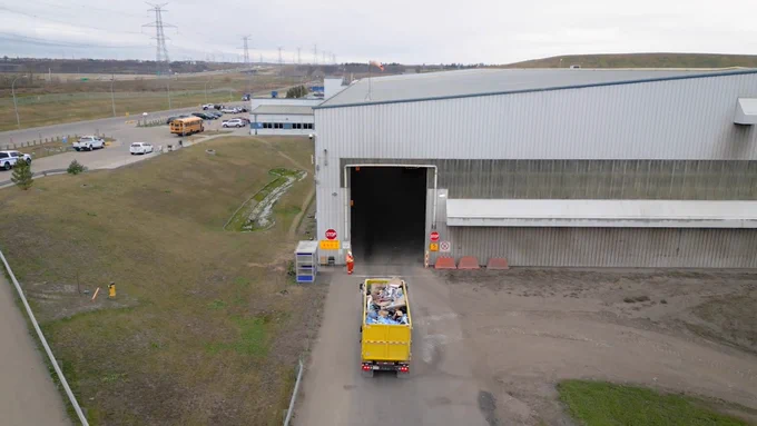 An open construction truck carrying waste drives into a warehouse.