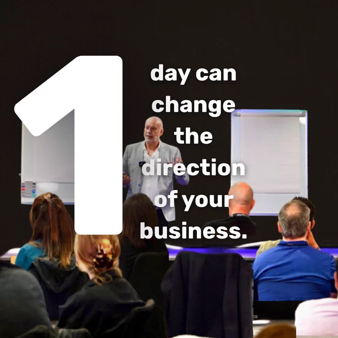 A business seminar with a presenter speaking to an engaged audience. The mood suggests motivation and learning.