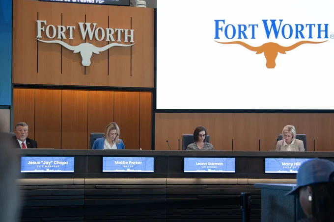 A group of people seated at a panel in a conference room with "Fort Worth" branding displayed on screens behind them. Nameplates on the table read: Jesus "Jay" Chapa, Mattie Parker, Leon Guzman, and Macy Hill.