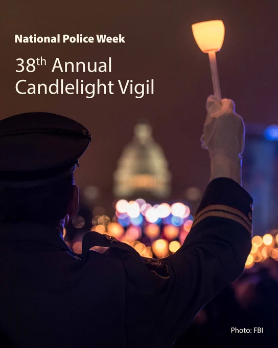 A person in a formal law enforcement uniform holds a lit candle with the lights of the United States Capitol on the horizon.