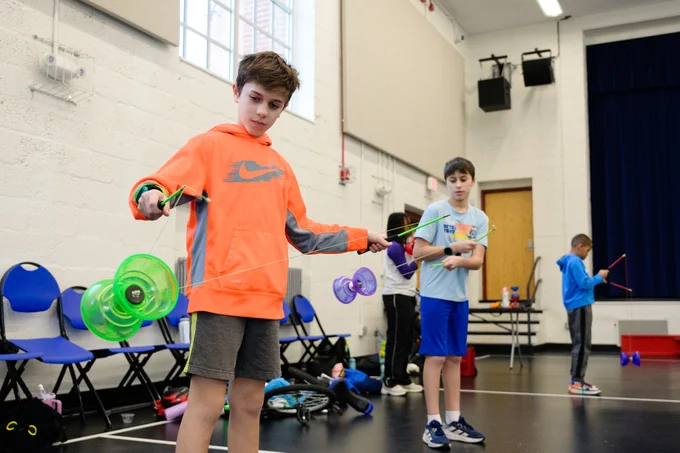 Children practice a circus trick they learned at a camp.