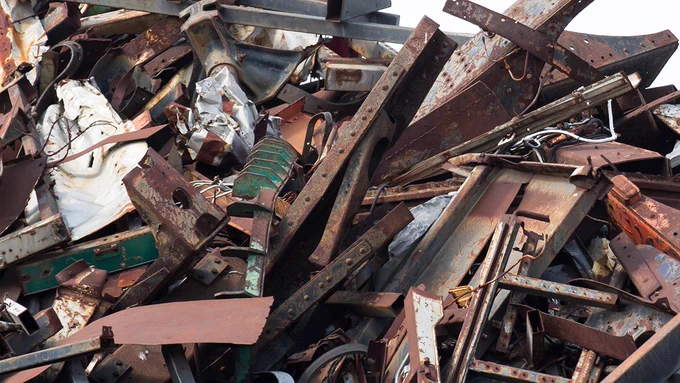 Photograph showing a large pile of rusted and damaged metal scrap, including beams, sheets, and various structural components.