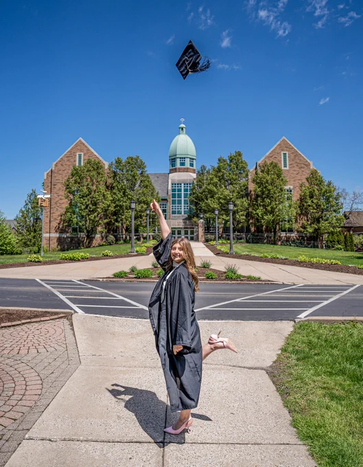 A student throwing her grad cap in the air. 