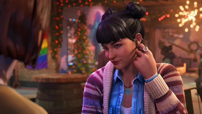 Amanda Thomas from Life is Strange: Double Exposure, an Indigenous woman of Cherokee and Algonquin descent, sitting inside her bar, The Snapping Turtle, located in Lakeport, Vermont. She has dark hair styled in space buns with blunt bangs, and is wearing a blue denim shirt, a striped knit cardigan, and a turquoise necklace. Amanda is looking up with a subtle, charming smile while adjusting a wireless earbud in her left ear. The blurry silhouette of Max Caulfield is visible in the foreground on the left, while the bar's warm interior with festive holiday lights creates a cozy background.