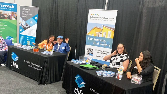 Four CHFA staff sitting at the CHFA swag and informational table at the NAHRO conference. 