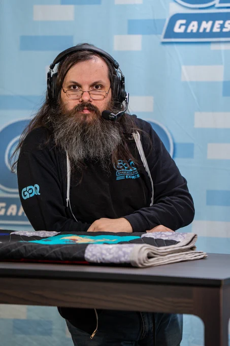 sent staring into the camera with a serious face and leaning on a table with a folded quilt