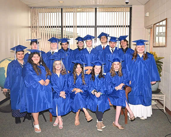 Fifteen students in caps and gowns.