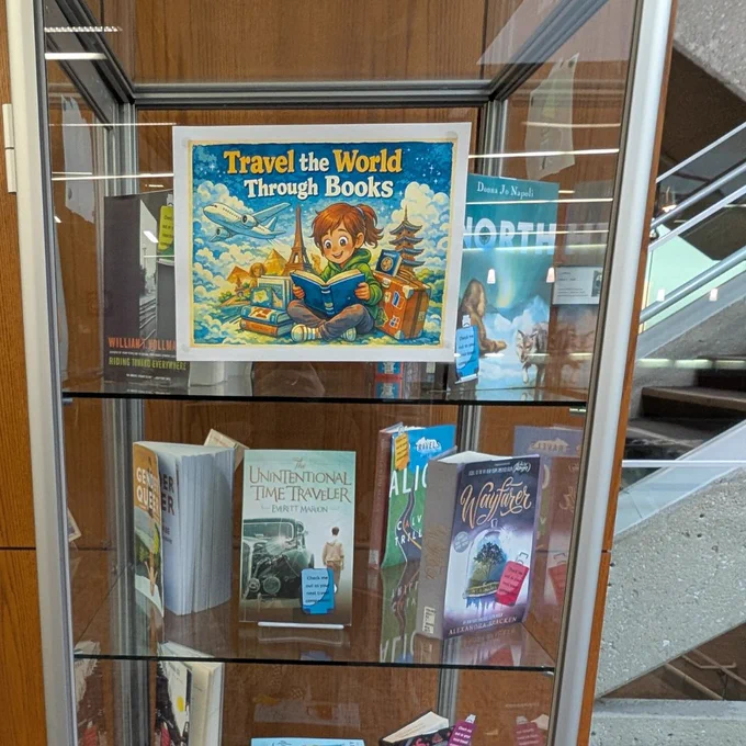 A glass and metal library display case with books in the case. There are pictures visible on the front of the case.