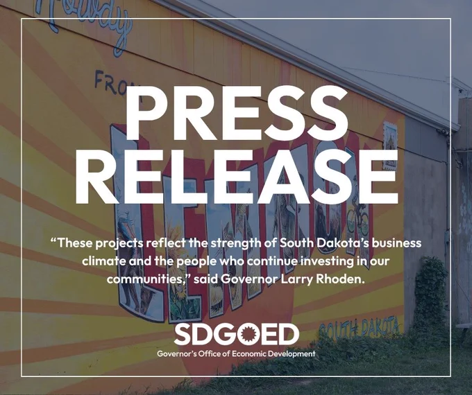 A mural with colorful letters spelling "Greetings from South Dakota" is painted on a wall. In front of the mural, the text reads: "PRESS RELEASE." Below, a quote says, "These projects reflect the strength of South Dakota's business climate and the people who continue investing in our communities," attributed to Governor Larry Rhoden. The image is labeled "SDGOED Governor's Office of Economic Development.