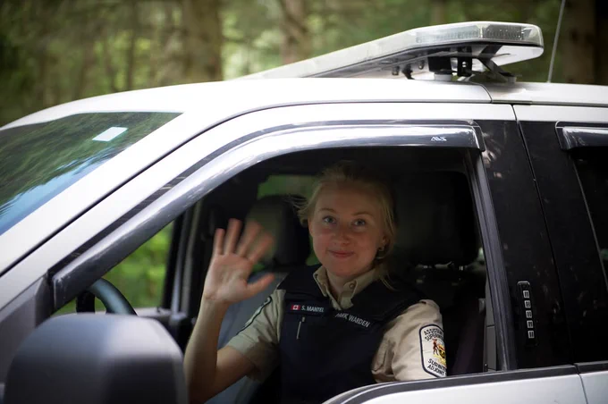 Park warden waving while sitting in a vehicle.