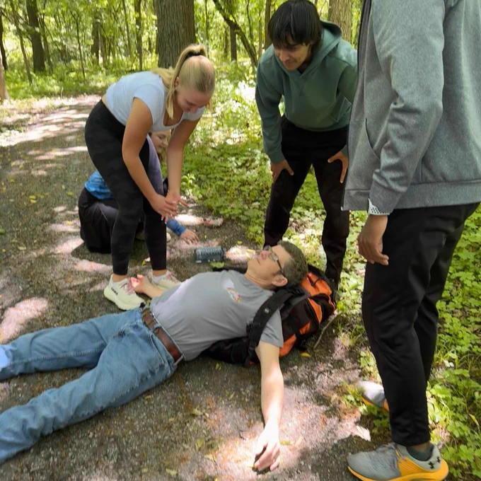 A group of people assisting an injured person on a forest trail.