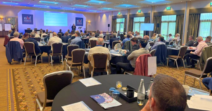 NBF Spring Forum and AGM attendees seated at round tables listening to Tristine Hargreaves presenting on stage