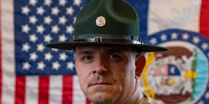 Missouri State Park Ranger in uniform standing in front of American and Missouri state flags.